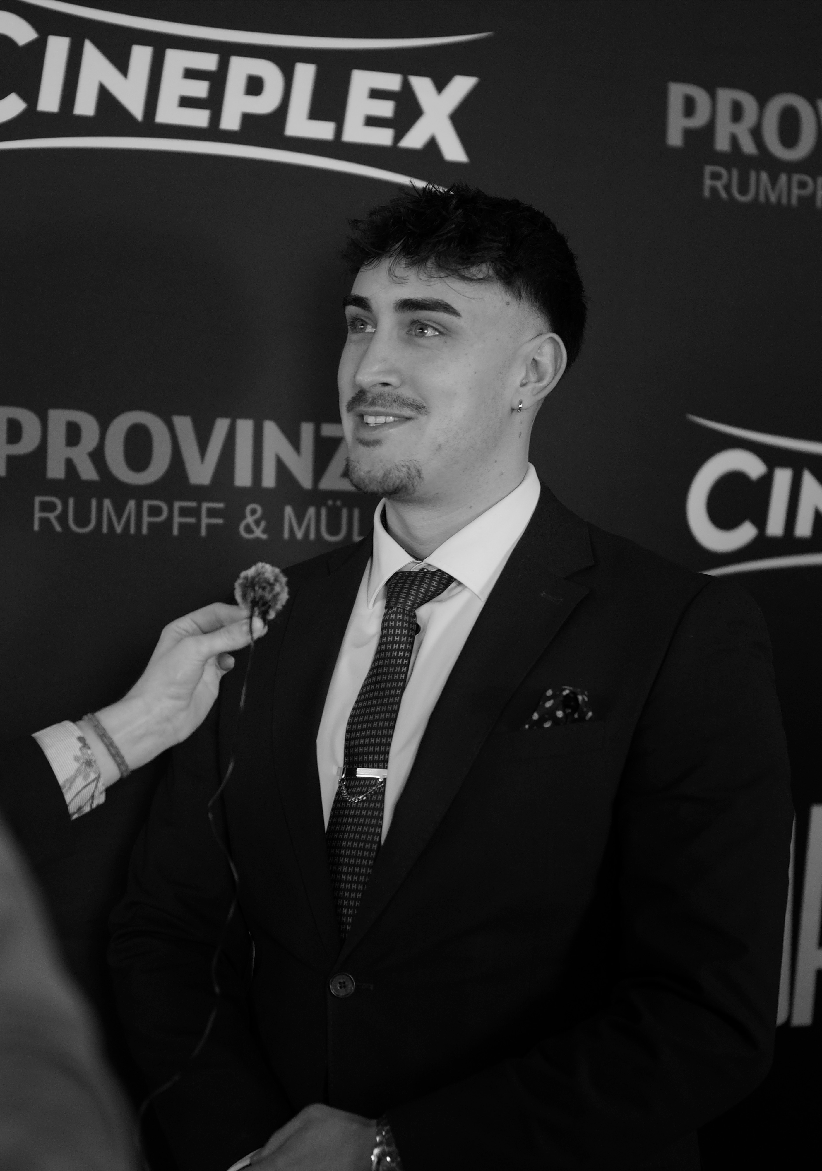 Oggi, founder and FPV pilot of CINELYFT, on a red carpet press wall